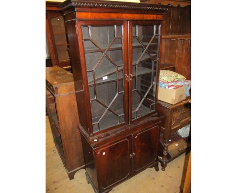 Small reproduction mahogany bookcase, the moulded key pattern cornice above a pair of astral glazed doors, the base with two 