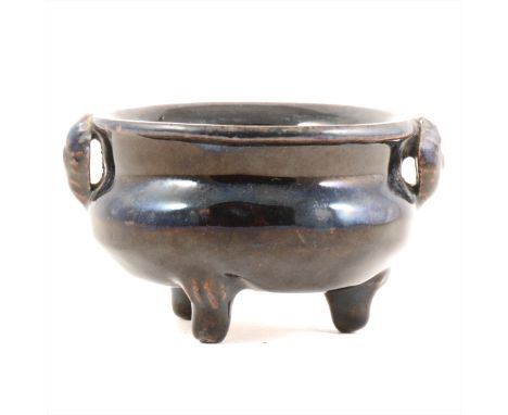 Chinese grey stoneware black glazed tripod censer, possibly Northern Song, rudimentary twin mask head handles, and raised on 