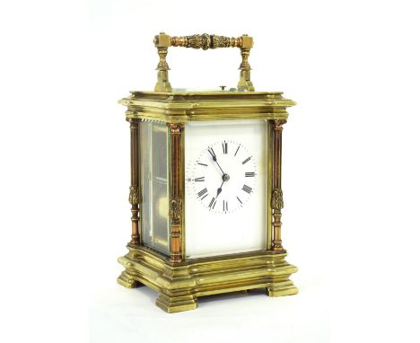 Large brass repeating carriage clock striking on a gong, within a pillared stepped breakfront case surmounted by an ornate ha