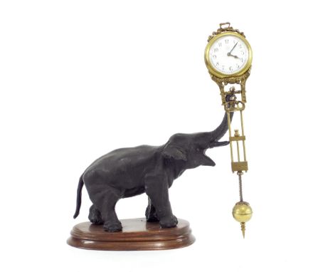 Junghans elephant mystery clock, the 1.75" white dial and pendulum held aloft by the trunk, upon a stepped shaped mahogany ba