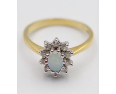 An 18ct gold opal and diamond cluster ring, claw set with an oval stone, bordered by 10 brilliants, size O 1/2, 4 gms. 