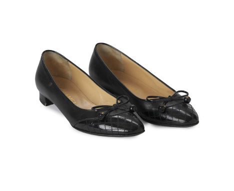 Chanel, a pair of black leather pumps, crafted with black leather uppers, with a quilted black patent leather toe cap and bow