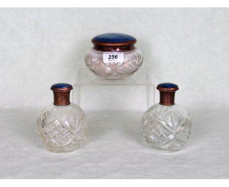 Three cut glass dressing table jars, the covers having blue enamel inlay.