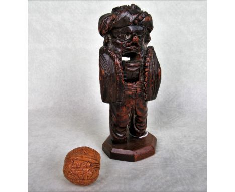 An early 19th century boxwood lever action nutcracker, to later wooden stand, 19cm, together with an Oriental carved walnut.