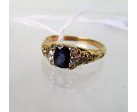 A sapphire and diamond nine stone half-hoop ring, the central oval cut sapphire with mixed cut diamond shoulders, pierced and