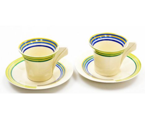 A pair of Clarice Cliff Bizarre coffee cans and saucers, of Art Deco design, each with a conical block handle and decorated w