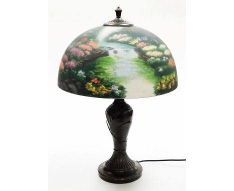 A Thomas Kinkade table lamp, the reverse decorated shade decorated with a meadow scene, on a cast metal base, 57cm high. 