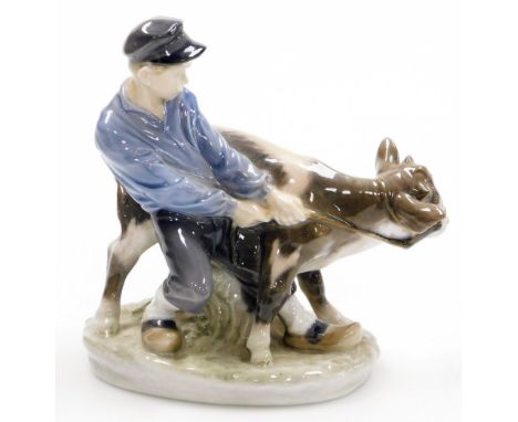 A Royal Copenhagen porcelain figure of a young boy and cow, on an oval base, green printed mark to underside and blue wave ma