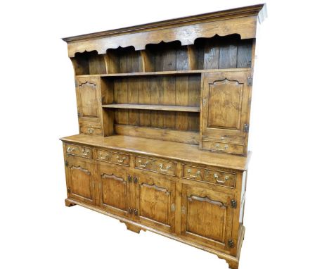 An oak and elm dresser, the plain moulded top with a carved under section and four open shelves, a further open shelf flanked