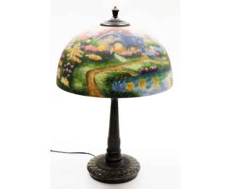 A Thomas Kinkade table lamp, the reverse decorated shade decorated with a lake and cottage scene, on a cast metal base, 57cm 