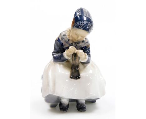 A Royal Copenhagen porcelain figure of a young girl sewing, green printed stamp and blue wave mark to underside, 14cm high.