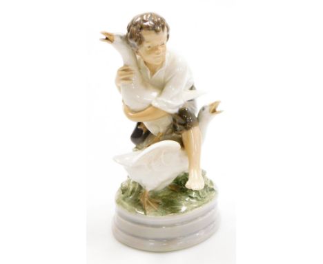 A Royal Copenhagen porcelain figure of a young boy fighting geese, on a circular base, green printed stamp and blue wave mark