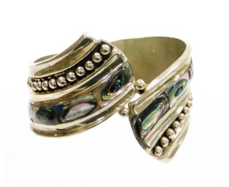 A Mexican mother of pearl set hinged bangle, of curved design, white metal unmarked, 6cm diameter.