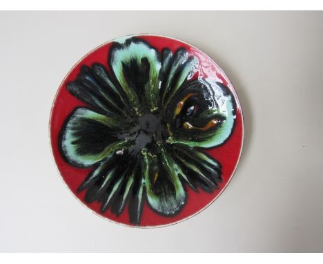 A Poole Delphis plate, red ground with green and black detail. 20.5cm diameter 