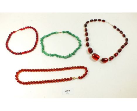 A red glass bead necklace a 'jade' chip necklace and two amber/Bakelite style necklaces 