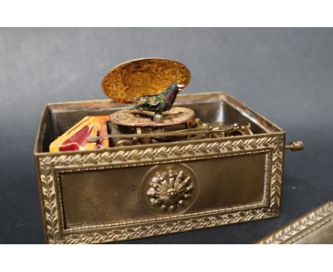 A gilt metal singing bird automaton music box, with a rectangular top decorated with leaves, the hinged oval sprung lid decor