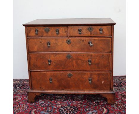 An 18th century walnut chest, the rectangular crossbanded top above two short and three long graduated drawers on bracket fee