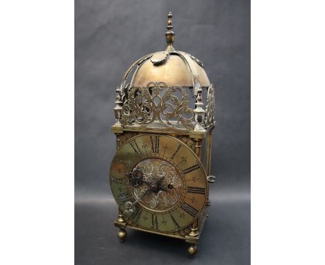 A Brass Lantern clock, the domed top housing a bell, with floral and leaf pierced panels, the circular brass dial with Roman 