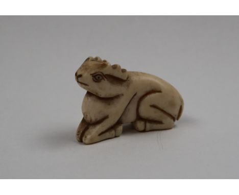 A late 19th century bone netsuke of a recumbent deer, signed to the base, 4cm long