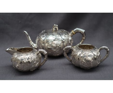 A Chinese silver three piece teaset, comprising a teapot, cream jug and twin handled sugar basin, of compressed circular form