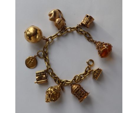 An 18ct yellow gold oval link bracelet, set with numerous 9ct yellow gold charms including a castle, cat, globe, typewriter, 