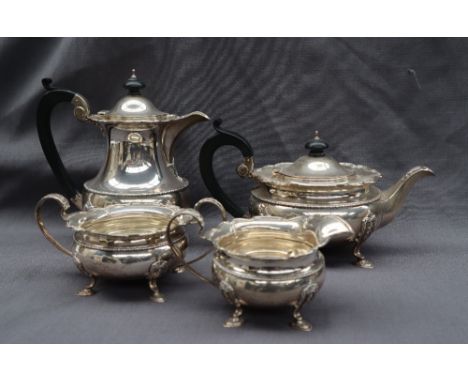 A George V silver four piece tea set, comprising a hot water pot, tea pot, cream jug and twin handled sugar basin, with a fla