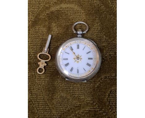An engraved .935 silver ladies pocket watch with gilt enamel Roman numeral dial and working movement, complete with key.