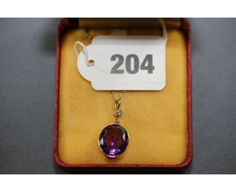 AN OVAL GOLD MOUNTED AMETHYST PENDANT with diamond set suspension loop.   