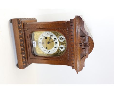AN EDWARDIAN CARVED OAK CASED MANTLE CLOCK, arched brass and silvered dial with chime/silent and fast/slow subsidiary dials, 