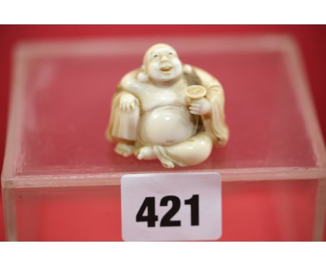 AN EARLY 20TH CENTURY JAPANESE CARVED IVORY NETSUKE depicting Hotei seated with a cup, red signature tablet to base, 1 1/2 in