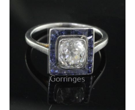 A 1920's/1930's platinum, diamond and sapphire cluster ring, of tablet form, the central cushion cut diamond weighing approxi