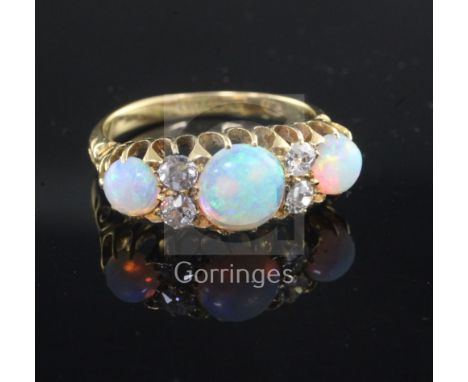 An Edwardian 18ct gold, white opal and diamond ring, set with three oval opals and four round cut diamonds, size P.