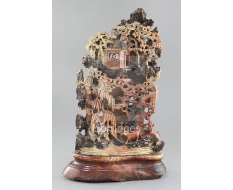 A Chinese soapstone boulder carving, 19th century, carved in high relief and open work with figures amid pavilions and trees,