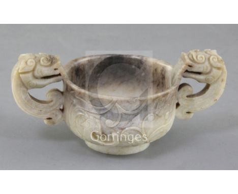 A Chinese cream and black jade two handled cup, 16th/17th century, carved in relief with chi-dragons and with a pair of chi-d