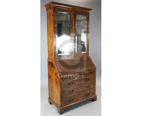 An early 18th century burr walnut bureau bookcase, with bevelled mirrored doors enclosing adjustable shelves and three short 