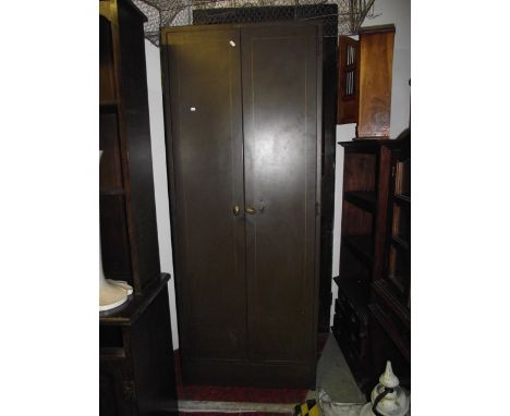 A vintage floorstanding painted steel industrial office cabinet enclosed by a pair of full length rectangular doors, the inte