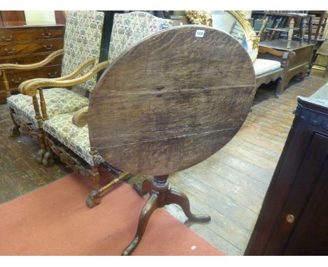 A Georgian oak snap stop occasional table of circular form raised on a turned vase shaped pillar and tripod