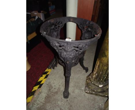 A cast iron pub table with swept tripod supports, face mask and pierced floral detail (lacks a circular top) 