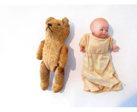 A small bisque head doll and a vintage straw filled teddy with bead eyes
