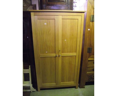 A contemporary light oak wardrobe enclosed by a pair of full length twin panelled doors, the interior fitted with a hanging r