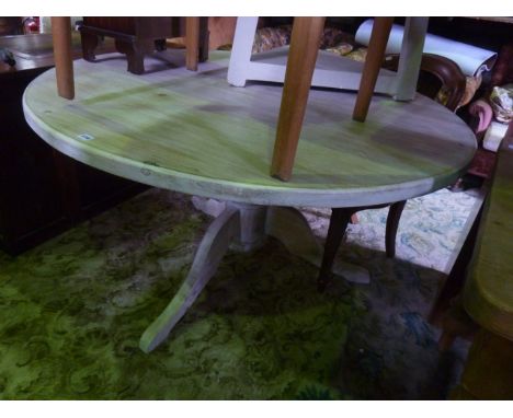 A bleached pine dining table of circular form, the heavy plank top raised on a turned pillar and tripod base, 135 cm in diame