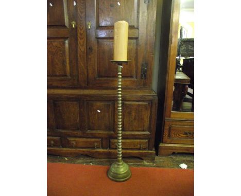 A floor standing heavy brass pricket candlestick with graduated ring stem and domed disc shaped base with engraved detail