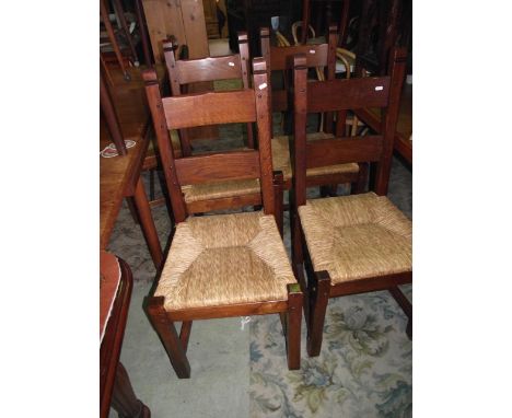 A set of four oak ladder back dining chairs with rush seats raised on square, cut and chamfered supports united by H shaped s