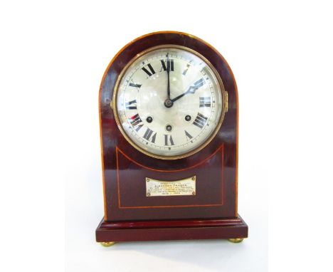 A late Edwardian mahogany mantel clock with arched case with string inlay detail, the silvered dial enclosing a three train m