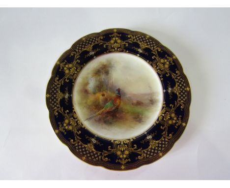 A Royal Worcester cabinet plate with painted central panel of a pair of pheasants in a landscape, within a dark blue, gilt an