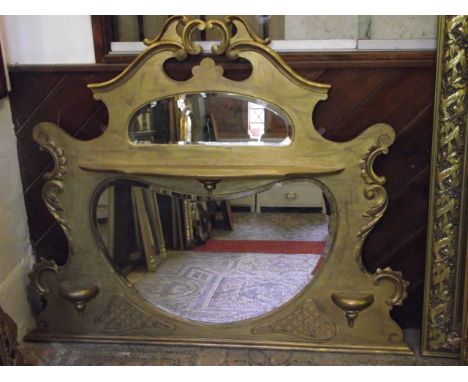 An Edwardian overmantel mirror with shaped outline, c-scroll and further detail, later gilded finish and enclosed by two kidn