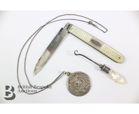 A silver and mother of pearl fruit knife approx. 9cm closed, a button hook approx. 7.5cms, and a silver pendant on a chain.&n
