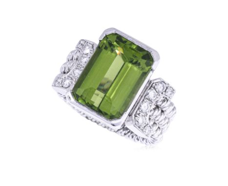 A PERIDOT AND DIAMOND RING BY KOJI IWAKURA
The emerald cut peridot, weighing approximately 9.02cts (marked), flanked by round