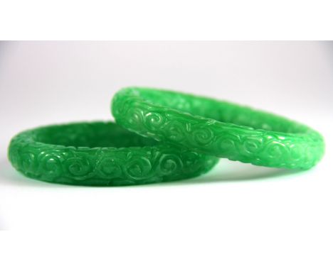 A pair of carved apple green jade bangles, W. 13mm internal Dia. 6cm.