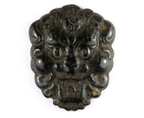 A Chinese carved dark jade amulet of a lion head, H. 8cm.